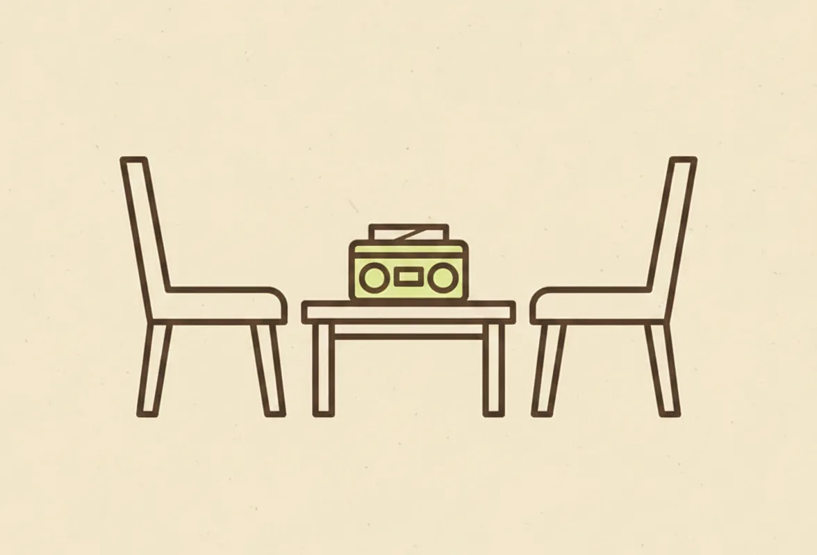 Two empty chairs facing each other across a small table holding a tape recorder