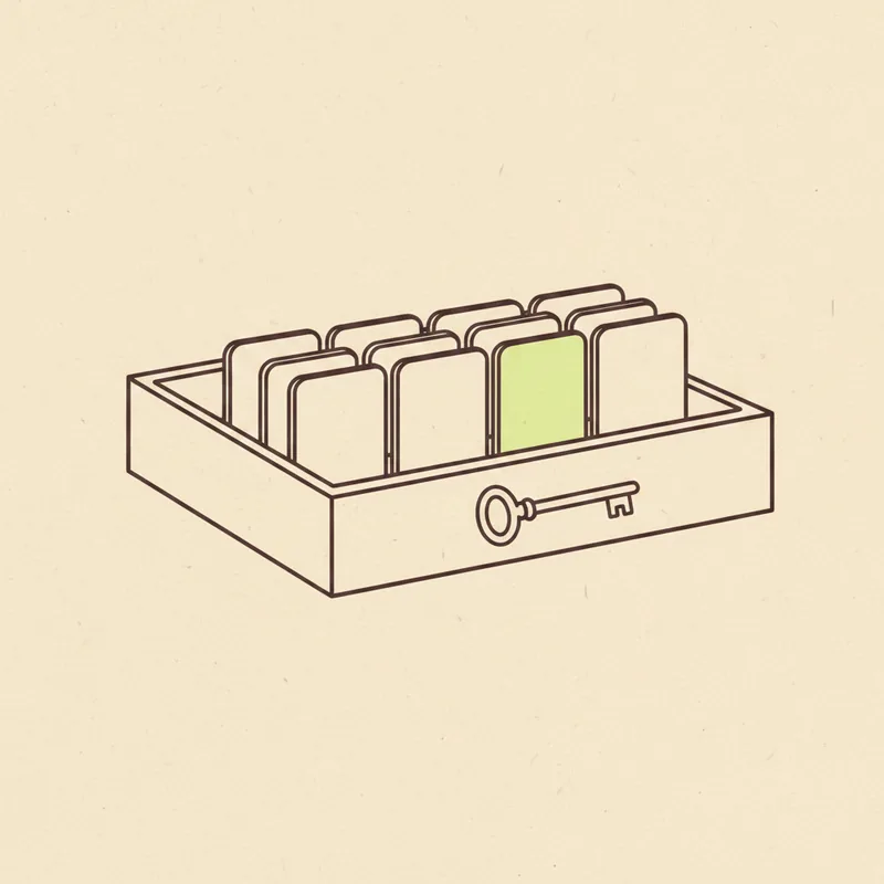 An open card-index drawer holding a row of upright blank divider cards, one card tinted pale green, a small key on the drawer front